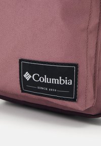 Borsa in tessuto rosa Columbia con finitura testurizzata, che presenta un'etichetta nera con la scritta "Columbia Since 1938".