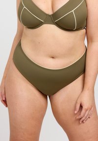 Olivegrön bikinitopp med vadderade kupor, accentuerad med krämfärgad piping, matchad med högmidjade bikinitrosor. Slät textur.