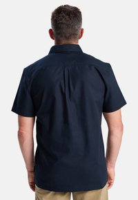 Korte mouwen marineblauwe shirt met een klassieke kraag, textuurstof en een plooi in het midden achter voor meer bewegingsvrijheid. Tailored fit ontwerp.