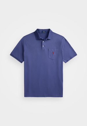 Violeta polo krekls, izgatavots no kokvilnas, ar trīs pogām, īsām piedurknēm un krūšu kabatu ar sarkanu logo izšuvumu.