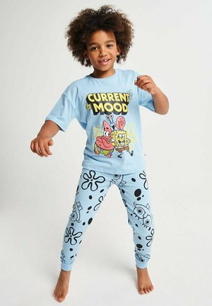 Child with curly hair wearing light blue SpongeBob-themed pajamas with "Current Mood" text, standing barefoot on a white background.