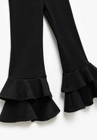 Schwarze Schlaghosen aus dehnbarem Stoff, mit Rüschensäumen an den Bündchen für zusätzlichen Volumen und Detail.