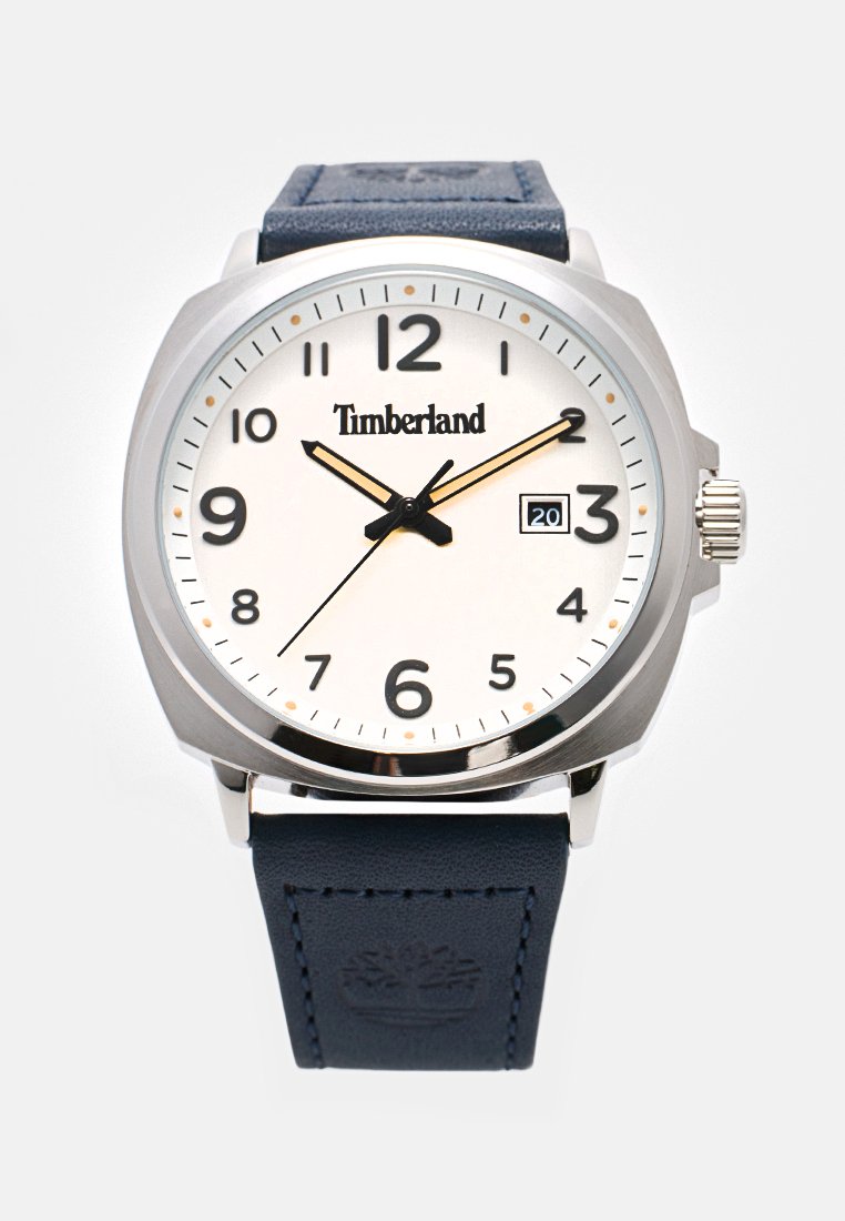 Orologio in acciaio inossidabile argentato con quadrante bianco, numeri arabi neri, una finestra della data e un cinturino in pelle blu navy. Logo Timberland esposto.