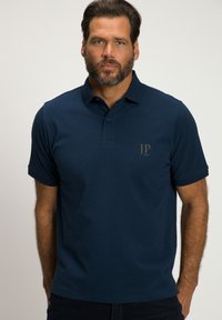 Polo marine en tissu doux, avec un col à deux boutons et un petit logo sur la poitrine gauche. Manches courtes et ourlet droit.