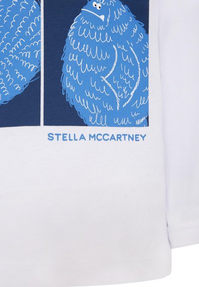 T-shirt bianca in cotone con illustrazioni grafiche blu di una creatura soffice e la scritta "STELLA McCARTNEY" sottostante in azzurro chiaro.