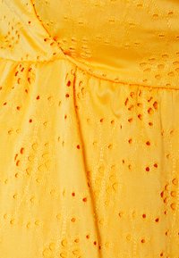 Gulldress stoff med en teksturert overflate, som har utskårne mønstre og små broderte detaljer. Jevnt, lett materiale.