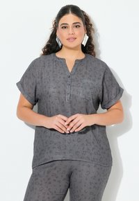 Camicia grigia a maniche corte con bottoni, scollo a V, stampa leopardo discreta, taschino sul petto e maniche arrotolate, realizzata in tessuto leggero e testurizzato.
