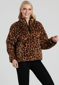 Leopardmønstret fleecepullover med halvlange lynlås foran, høj krave, afslappet pasform og tekstureret stof. Sorte detaljer ved manchetterne og kanten.