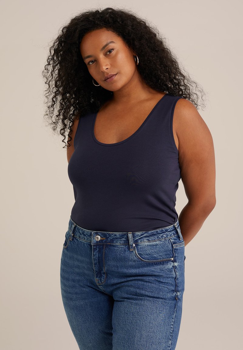 Top sin mangas de color azul marino hecho de una tela suave con escote redondeado, combinado con jeans de mezclilla azul texturizados de tiro alto.
