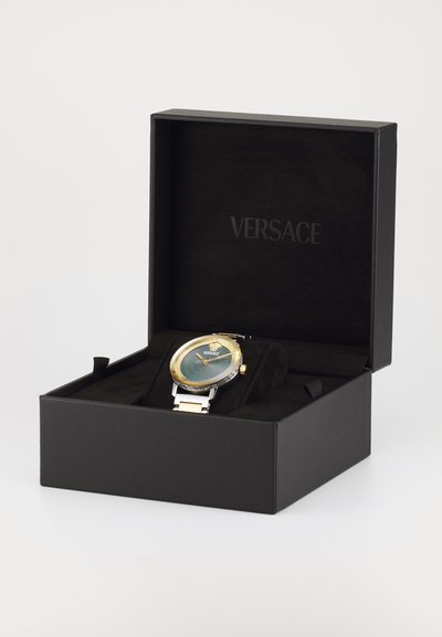 Versace pulkstenis ar apaļu zaļu un zelta ciparnīcu, sudraba nerūsējošā tērauda siksniņu un detalizētu rāmīti, izrādīts melnā prezentācijas kastē.
