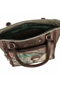 Sac en synthétique marron avec un décor artistique sur le devant, représentant une fille et du texte. Comprend une poche intérieure et des accents en métal.