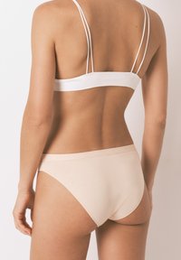 Světle růžové bavlněné bikiny s měkkým, elastickým pasem. Obsahuje tenké bílé nastavitelná ramínka na odpovídající podprsence.