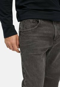 Gray denim jeans with a slightly faded look, five-pocket design, and subtle stitching details. Paired with a black long-sleeve shirt.