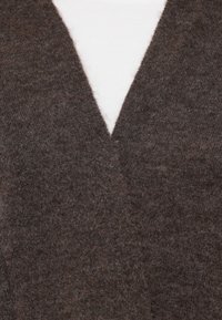 Cardigan tricoté marron avec un design en V, fabriqué à partir d'un matériau moelleux semblable à de la laine, présentant une texture douce et des détails minimaux.