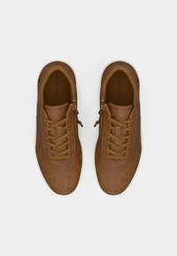 Brown leather sneakers with a rounded toe, lace-up front, and perforated detailing. Features a textured surface and white rubber sole.