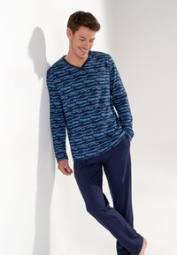Top a maniche lunghe blu navy con scollo a V caratterizzato da un motivo astratto blu chiaro, abbinato a pantaloni scuri; vestibilità comoda e tessuto morbido.