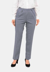 Grijze op maat gemaakte broek met een elastische tailleband en zijzakken, met een subtiel ruitpatroon. G gedragen met zwarte hakken.