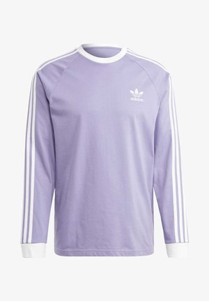 Lavendelkleurig Adidas shirt met lange mouwen, witte ronde hals, witte manchetten en drie witte strepen die langs elke mouw lopen.