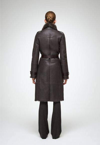 Manteau en cuir marron foncé avec col en fourrure, taille ceinturée et ourlet en laine. Présente des épaules structurées et des manches longues.