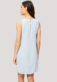 Vestido sin mangas de color azul claro, confeccionado en una tela suave, con un detalle de ojal en la parte posterior y un corte relajado. El dobladillo es ligeramente redondeado.