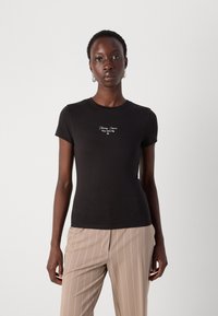 T-shirt corto nero a maniche corte in cotone, con testo ricamato bianco sul petto. La vestibilità è ampia, con un design a collo rotondo.