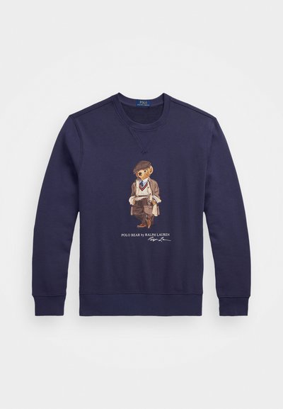 Sweatshirt en coton bleu marine mettant en avant un graphique d'ours vêtu d'une tenue tailleur, avec des poignets et un col côtelés. Texte "Polo Bear by Ralph Lauren" inclus.