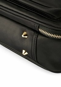 Czarna torba nylonowa z złotymi stożkowymi nitami, z zamkiem błyskawicznym i fakturowanymi akcentami. Posiada gładki materiał i strukturalny kształt.