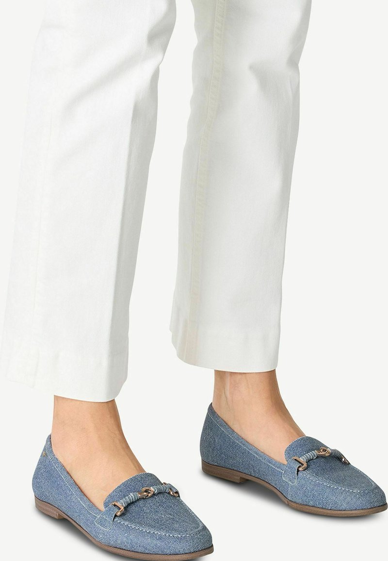 Zilas denim loafers ar platu zoli, ar austu akcentu un nelielu metāla detaļu virsējā daļā, kombinēti ar baltām īsām biksēm.