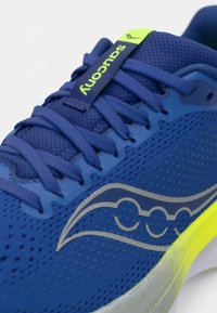 Bottine de course bleue avec tige en mesh, surface texturée, logo argent réfléchissant, accents jaune fluo et système de laçage proéminent.