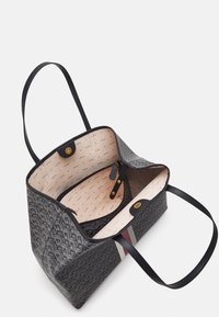 Czarna torba na ramię w wzory z jasnym wnętrzem. Posiada podwójne czarne uchwyty, zapięcia magnetyczne oraz wewnętrzną kieszeń na zamek.