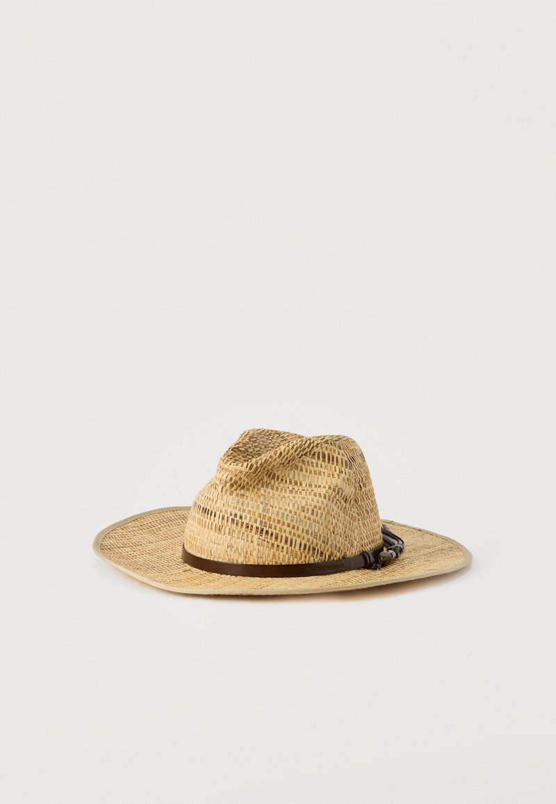Chapeau en paille tressée de couleur marron clair avec un large bord et un bandeau en cuir marron foncé orné d'une petite boucle, sur un fond uni.