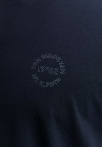 Tamnoplava majica od mekog pamuka, s tiskanim kružnim logotipom i natpisom: "TOM TAILOR TRM 1962 MT. X_PDTN."