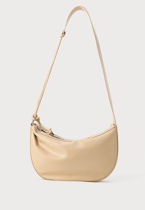 Borsa a spalla in pelle beige con forma curvata, dettaglio regolabile a nodo sulla tracolla e chiusura con zip. Logo in rilievo discreto sul davanti.