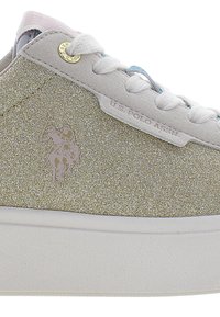 Glittery gold sneaker with a white sole, featuring laces and a pale pink accent. Includes a subtle logo of a rider on a horse.