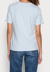 Camiseta de manga corta de color azul claro con cuello redondo, textura de algodón suave y corte relajado, combinada con unos pantalones vaqueros de corte holgado.