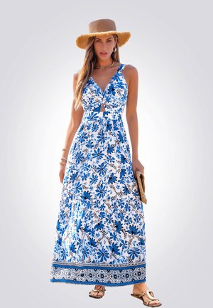 Maxi-jurk met een bloemenpatroon in blauw en wit, v-hals met een keyhole-details en een gelaagde rok. Gepaarde met een strohoed en sandalen.