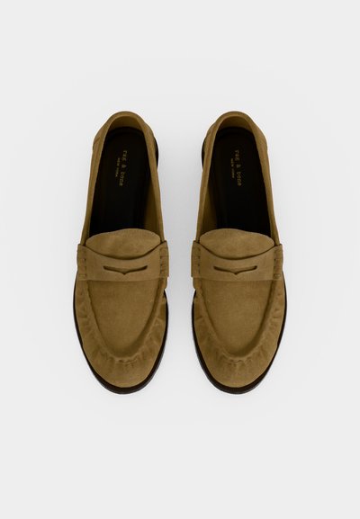 Paquet de mocassins en cuir suédé beige avec bouts arrondis et détail de bride décorative, vus de dessus sur fond blanc.