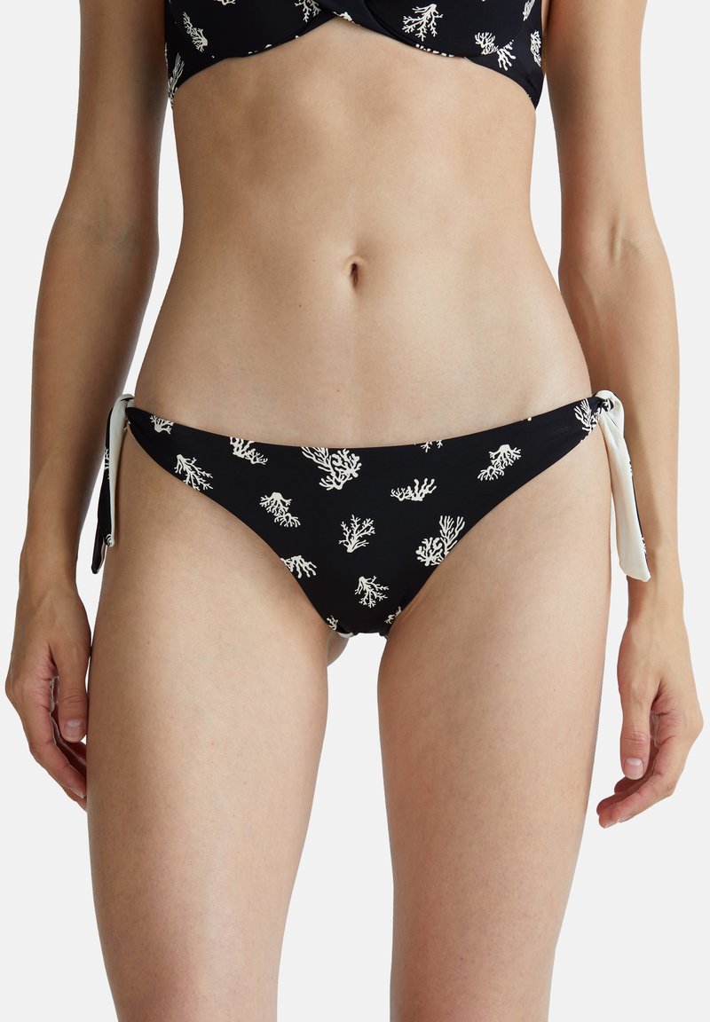 Černé bikini dno s bílým korálovým vzorem, má zavazování na bocích, hladkou texturu a nízký střih. Vhodné pro plážové nebo bazénové nošení.