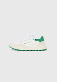 Witte sneaker met groene accenten en een textuur rubberen zool. Beschikt over suède details, vetersluiting en Lacoste branding aan de zijkant.