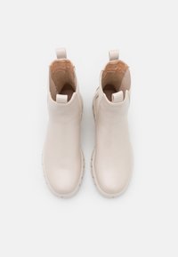 Jasno beżowe botki za kostkę wykonane z gładkiej skóry, z okrągłym noskiem, pętlą do zakupu i teksturowaną gumową podeszwą. Wnętrze wyłożone miękkim materiałem.
