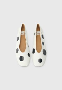 Baltos odinės balerinos su didelėmis juodomis taškeliais, apvaliomis nosytėmis ir elastingais kraštais. Viduje yra ruda vidpadė su prekės ženklo logotipu.