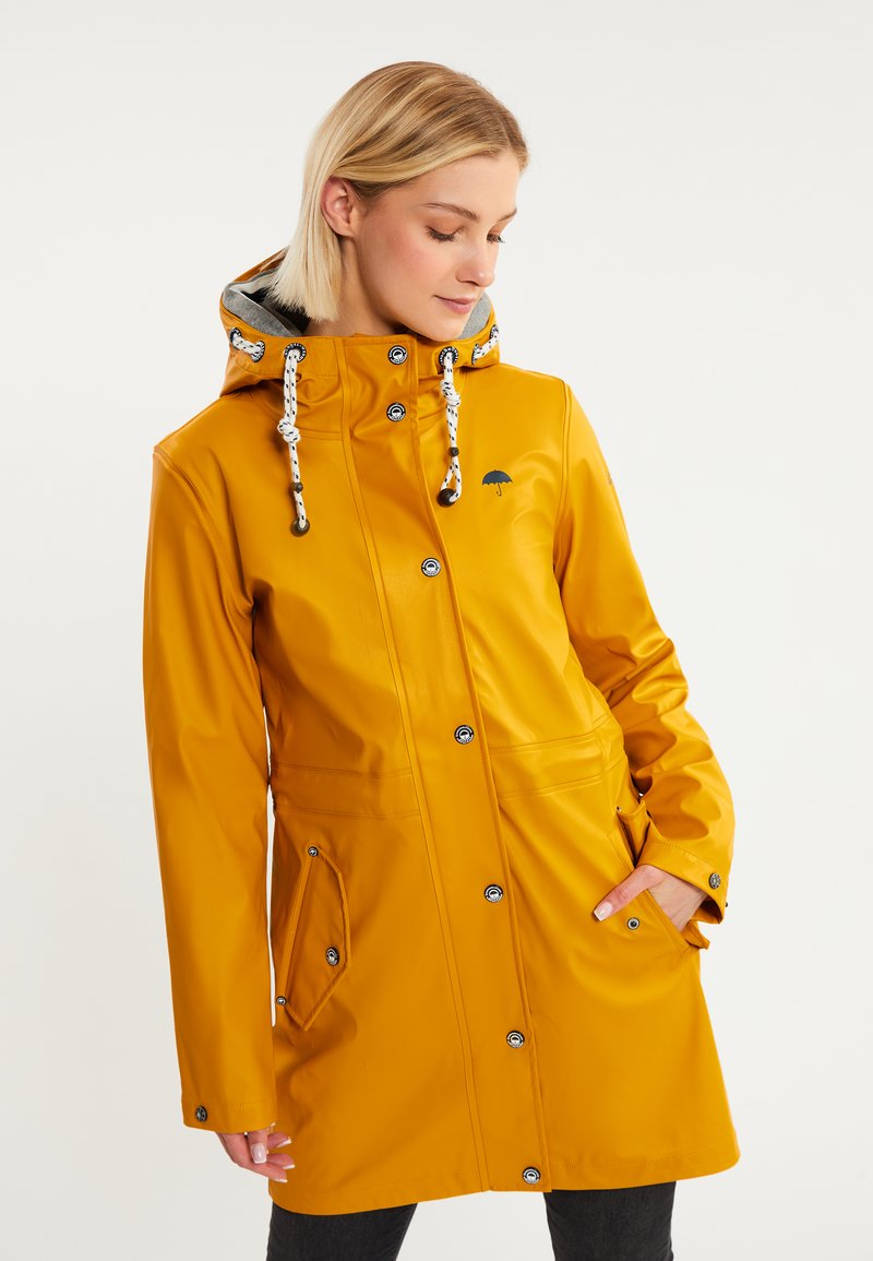 Chubasquero amarillo impermeable con un diseño ajustado, botones a presión, capucha con cordón y bolsillos laterales. Presenta un logo de paraguas negro en el pecho.