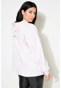 Rosa Batik-Hoodie mit lockerer Passform und fransigem Saum, kombiniert mit schwarzen, eng anliegenden Leggings. Weiches Material und lässiges Design.
