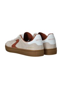 Zapatillas de ante crema con un logotipo lateral marrón, acentos blancos y una suela de goma marrón texturizada. Diseño con cordones y cuello acolchado.