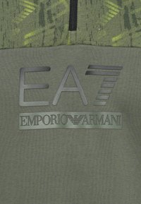 Sweatshirt verde-escuro com um padrão texturizado, com um logo preto brilhante a dizer "EA7 Emporio Armani" ao centro.