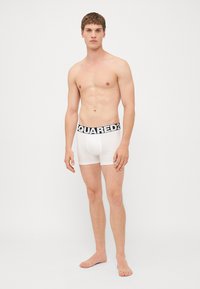 Weiße Boxershorts mit einem schwarzen "SQUARED2"-Bund. Der Stoff wirkt glatt und enganliegend, was ein minimalistisches Design betont.