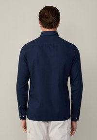 Marineblauw langemouwen shirt van katoen, met een klassieke kraag, knoopmanchetten en een gladde textuur. Achteraanzicht weergegeven.