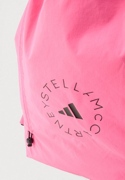 Φωτεινό ροζ σακίδιο πλάτης από ελαφρύ ύφασμα, με κυκλικό μαύρο λογότυπο με τρεις διαγώνιες ρίγες, φερμουάρ και υφή στην επιφάνεια.