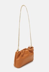 Petit sac à main en cuir marron avec une texture douce plissée et une longue bandoulière en chaîne dorée, incliné sur un fond blanc.