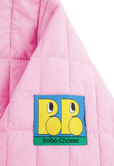 Tissu matelassé rose avec un patch cousu coloré montrant deux oiseaux dessin animés jaunes et le texte "Bobo Choses" sur une bande verte.